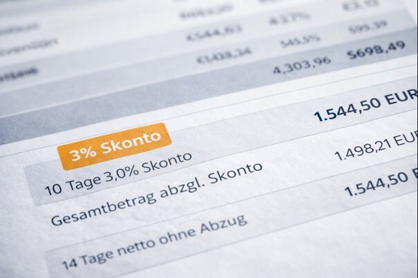 Ein Taschenrechner zeigt eine Zahl, davor liegt ein Zettel mit der Aufschrift 3 Prozent Skonto. Das Bild symbolisiert das Ersparnispotenzial von Skonto.